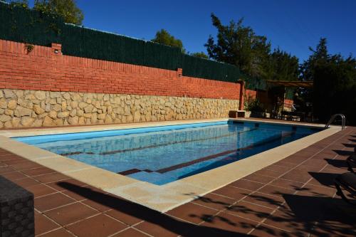 a swimming pool next to a brick wall at Villa Sitges Soledad 15 minutes drive from Sitges XXL swimming pool 12 p in Olivella