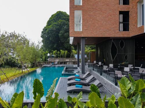 a swimming pool with lounge chairs and a building at VELA DHI Nakhon Phanom in Nakhon Phanom