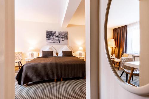 ein Hotelzimmer mit einem Bett und einem Spiegel in der Unterkunft Hotel-Restaurant Thüringer Hof in Bad Frankenhausen