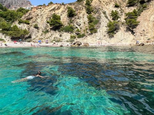 a person swimming in the water near a beach at Ático en Playa Altea - Puerto de Campomanes in Altea