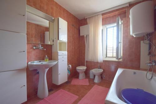 łazienka z umywalką, toaletą i wanną w obiekcie Apartment Potnar M w mieście Malinska