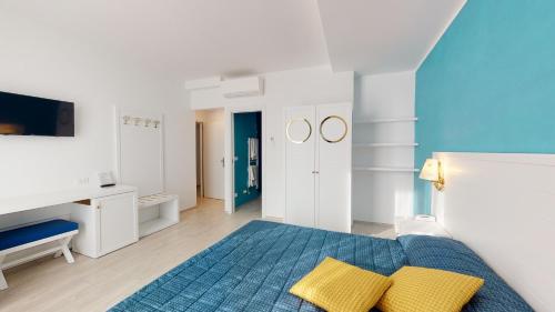 Dormitorio blanco y azul con cama y almohadas amarillas en Hotel Zunino, en Spotorno