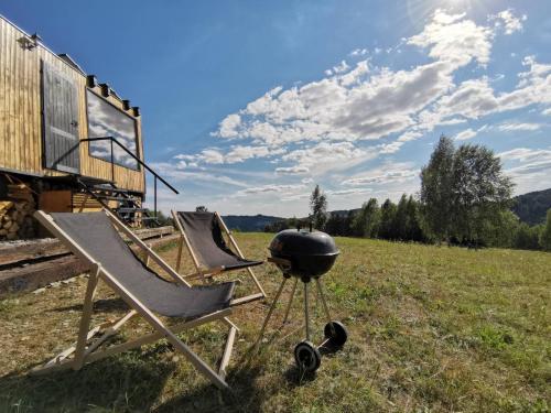 a grill and lounge chairs in a field at Zážitkový pobyt uprostřed přírody in Železný Brod