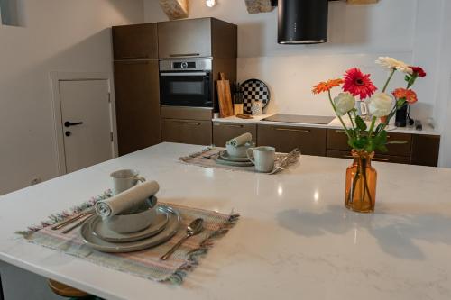 a kitchen counter with a table with a vase of flowers at Luxury 2BDR in the Heart of Valletta! TV and WiFi in Valletta