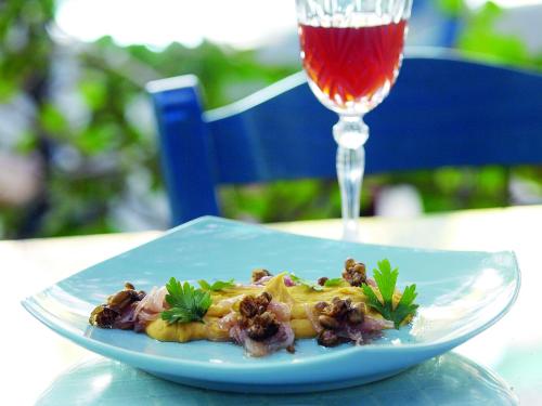 a plate of food on a table next to a wine glass at Poseidon Blue Gastronomy Hotel in Afiartis