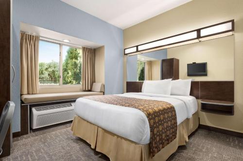 a hotel room with a large bed and a window at Microtel Inn & Suites by Wyndham Woodstock/Atlanta North in Woodstock
