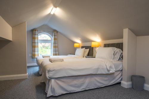 1 dormitorio con 2 camas con sábanas blancas y ventana en Escape Ordinary in Enniskillen, en Enniskillen