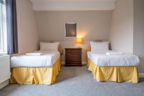 two beds in a room with a lamp on a table at Escape Ordinary in Enniskillen in Enniskillen