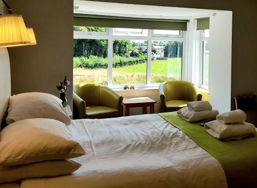 a large bed in a room with a large window at The White House Guest House in Penrith