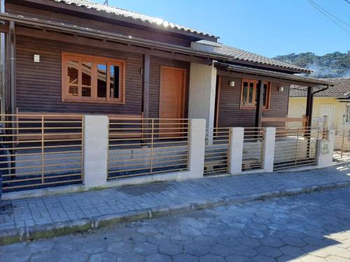 ein Holzhaus mit einem Zaun davor in der Unterkunft Águia Dourada Hospedagem Casa 01 in Bom Jardim da Serra