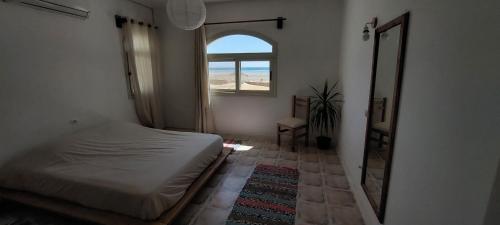 a bedroom with a bed and a mirror and a window at The white villas (TWV) in Ras Sedr