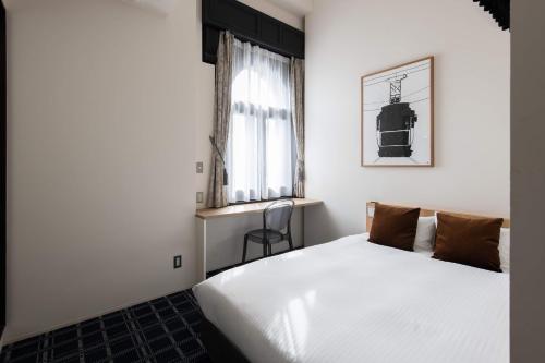 a bedroom with a white bed and a window at HakoBA Hakodate by THE SHARE HOTELS in Hakodate