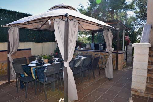 an umbrella on a patio with tables and chairs at Villa Sitges Ilusión 15 minutes by car from Sitges Sleeps 16 people XXL swimming pool in Olivella