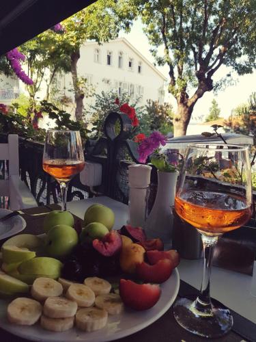 a table with a plate of food and two glasses of wine at Büyükada Anastasia Meziki History Mansion in Buyukada