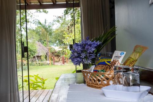 a table with a basket of food and a window at Pousada Recanto da Grande Paz in Alto Paraíso de Goiás