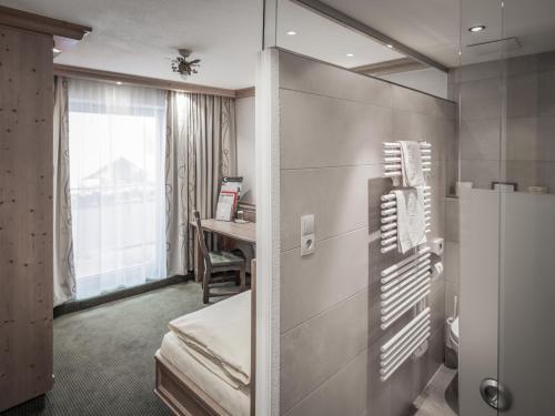una camera d'albergo con frigorifero e scrivania di Hotel Alpenland a Obergurgl