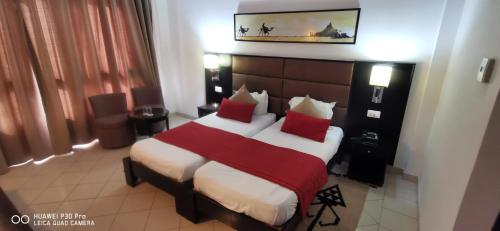 HOTEL OLYMPIC DJERBA في Djerba: غرفة نوم بسرير كبير ومخدات حمراء وبيضاء