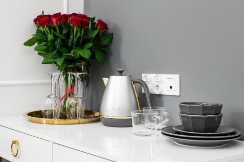 a counter with a vase of red roses and glasses at HOUSEHOST Apartment: Św.Gertrudy 10/2.11 in Krakow