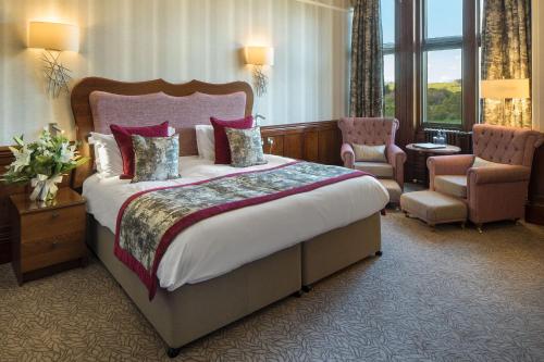 a hotel room with a large bed and a chair at Armathwaite Hall Hotel & Spa in Bassenthwaite