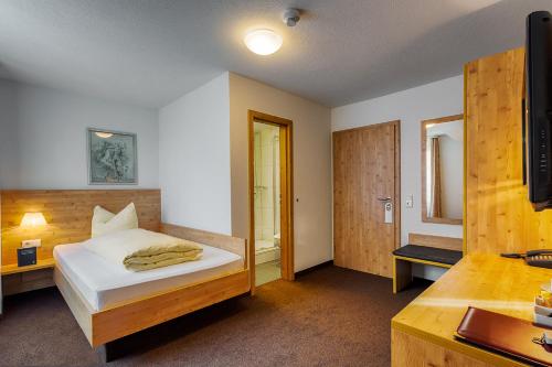 a bedroom with a bed and a desk with a television at Gasthaus zum Kranz in Lörrach