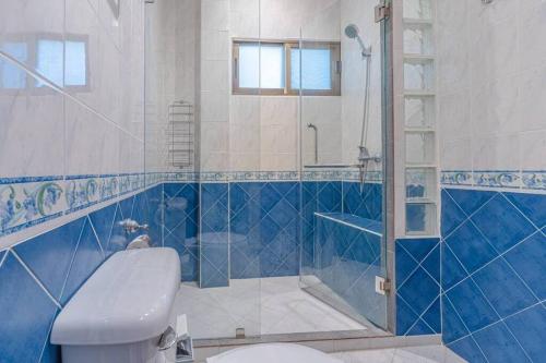 La salle de bains bleue et blanche est pourvue de toilettes et d'une douche. dans l'établissement Resort 5-3BR Huge Pool, BBQ, 300m-Beach, 8 mins to Walking Street, à Pattaya (sud)