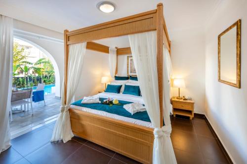 a bedroom with a canopy bed and a balcony at Peridis Family Resort in Kos Town