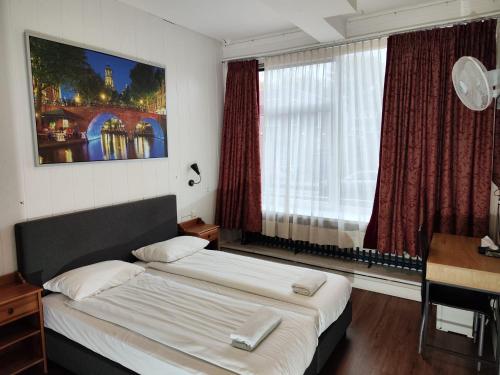 a bedroom with a bed and a desk and a window at Hotel Holland Lodge in Utrecht