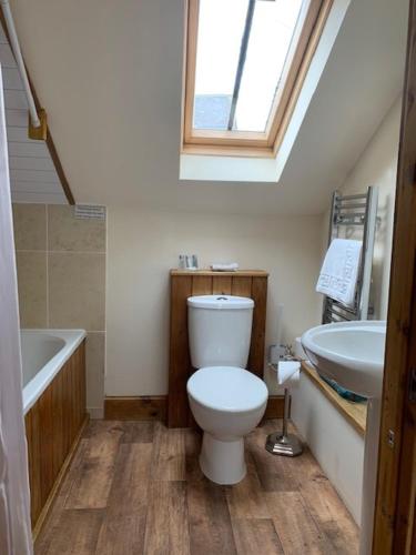 a bathroom with a toilet and a tub and a sink at Noble Lands in Wooler