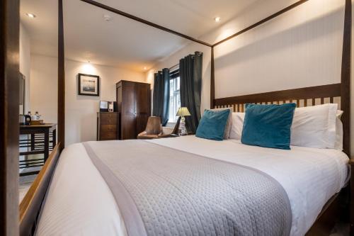 a bedroom with a large bed with blue pillows at The Howbeck & The Retreat Central location, incl off-site Health Club and parking EV point available, GREAT DEALS ON in Windermere