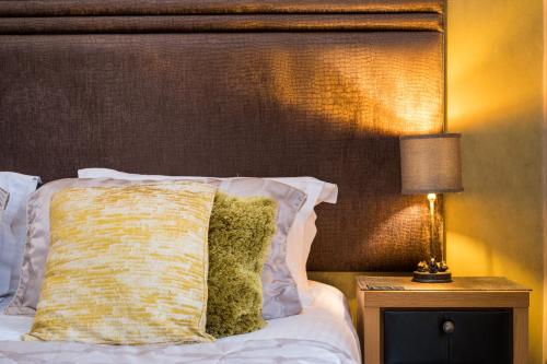 a bed with a pillow and a lamp on a night stand at The Howbeck & The Retreat Central location, incl off-site Health Club and parking EV point available, GREAT DEALS ON in Windermere