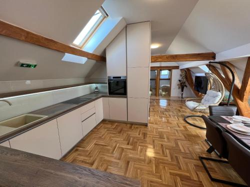 a kitchen with white cabinets and a wooden floor at La Luna Rustic Deluxe Apartment with Free Jacuzzi, Bikes & Covered Parking in Našice
