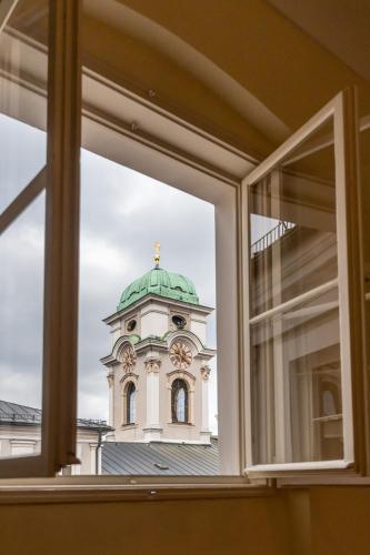 a building with a clock tower seen through a window at Gästehaus im Priesterseminar Salzburg in Salzburg