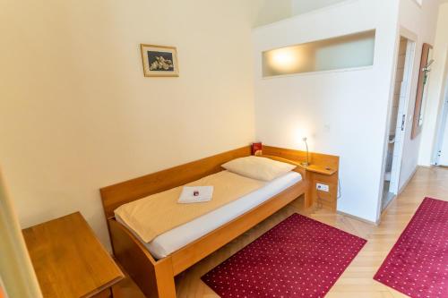 a small bedroom with a bed and a red rug at Gästehaus im Priesterseminar Salzburg in Salzburg