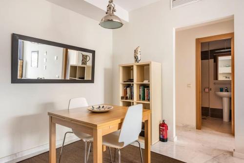 une salle à manger avec une table en bois et des chaises blanches dans l'établissement San Felipe, à Malaga