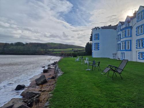 a row of chairs sitting on the grass next to a building at Balcary Bay Country House Hotel in Auchencairn