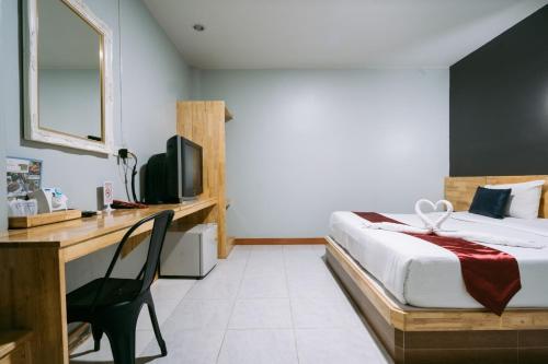 - une chambre avec un lit et un bureau dans l'établissement Jintana Resort, à Buriram