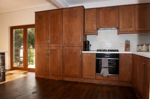 a kitchen with wooden cabinets and a stove top oven at The Old Mount Manor - Causeway Coast in Coleraine