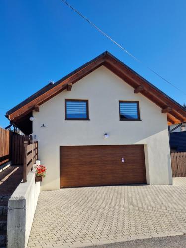 a white house with a brown garage door at Kukurooms in Koniaków