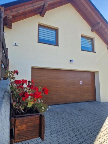 a garage with a wooden garage door and flowers at Kukurooms in Koniaków