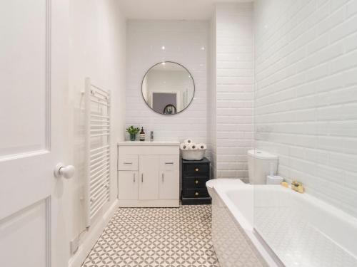 a white bathroom with a tub and a sink and a mirror at Pass the Keys Lovely 2 bed home in Larkhall with street parking in Bath