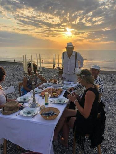 a group of people sitting around a table on the beach at La Baigneuse maison avec jardinet et parking privé, à 200 m plage in Cayeux-sur-Mer