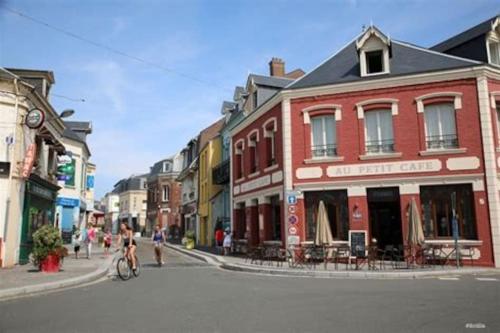 a street in a town with buildings and a person riding a bike at La Baigneuse maison avec jardinet et parking privé, à 200 m plage in Cayeux-sur-Mer