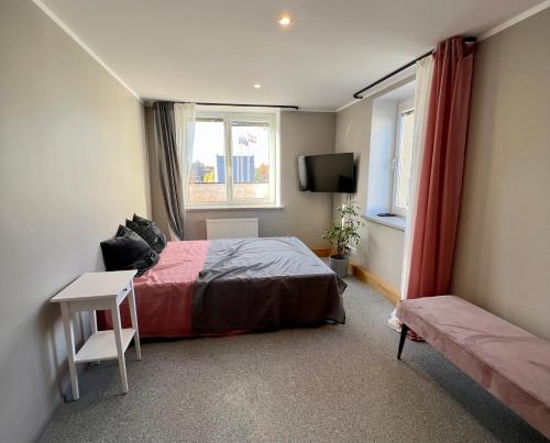 1 dormitorio con 1 cama, TV y ventana en Apartments in Dobele city center - Pilsētas Māja, en Dobele