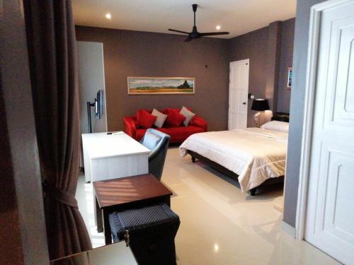 een slaapkamer met een bed en een rode bank bij Klong Muang Beach Apartment in Klong Muang Beach
