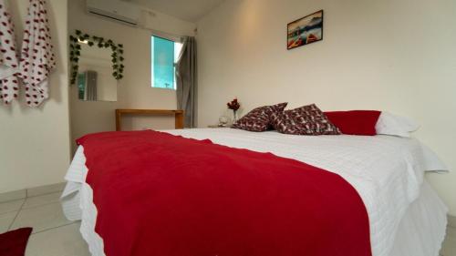 a bedroom with a red and white bed with pillows at POUSADA CENÁRIO IDEAL in Icapuí