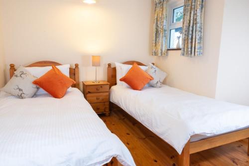 two twin beds in a room with a window at Nevins Newfield Inn Ltd in Mulranny