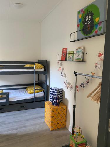 a bedroom with two bunk beds and a shelf at Bij het meertje! in Dirkshorn