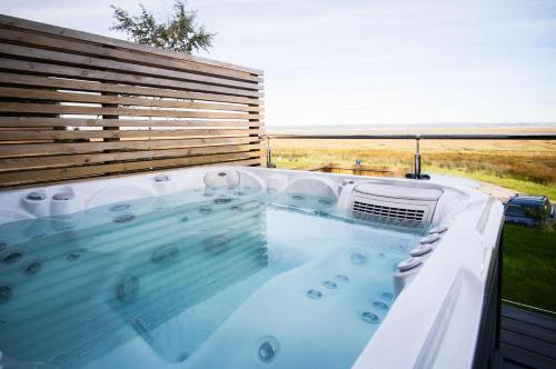 a hot tub with a view of the ocean at The Rhossili Bay Secret - 1 Bed Cabin - Landimore in Gowerton