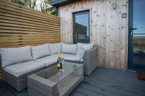 a patio with a couch and a table on a deck at The Rhossili Bay Secret - 1 Bed Cabin - Landimore in Gowerton