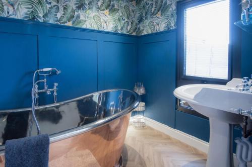 a blue bathroom with a tub and a sink at The Rhossili Bay Secret - 1 Bed Cabin - Landimore in Gowerton
